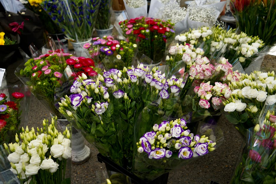 A variety of fresh floral bouquets arranged on a display table, featuring colorful flowers including purple and white eustoma, pink roses, red and white carnations, white lisianthus, and other mixed b